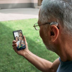 man with hearing aid listens to video call 
