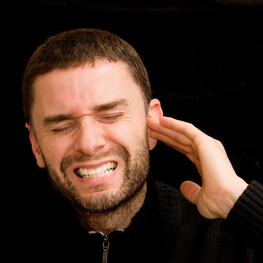 a man holding his ear in pain