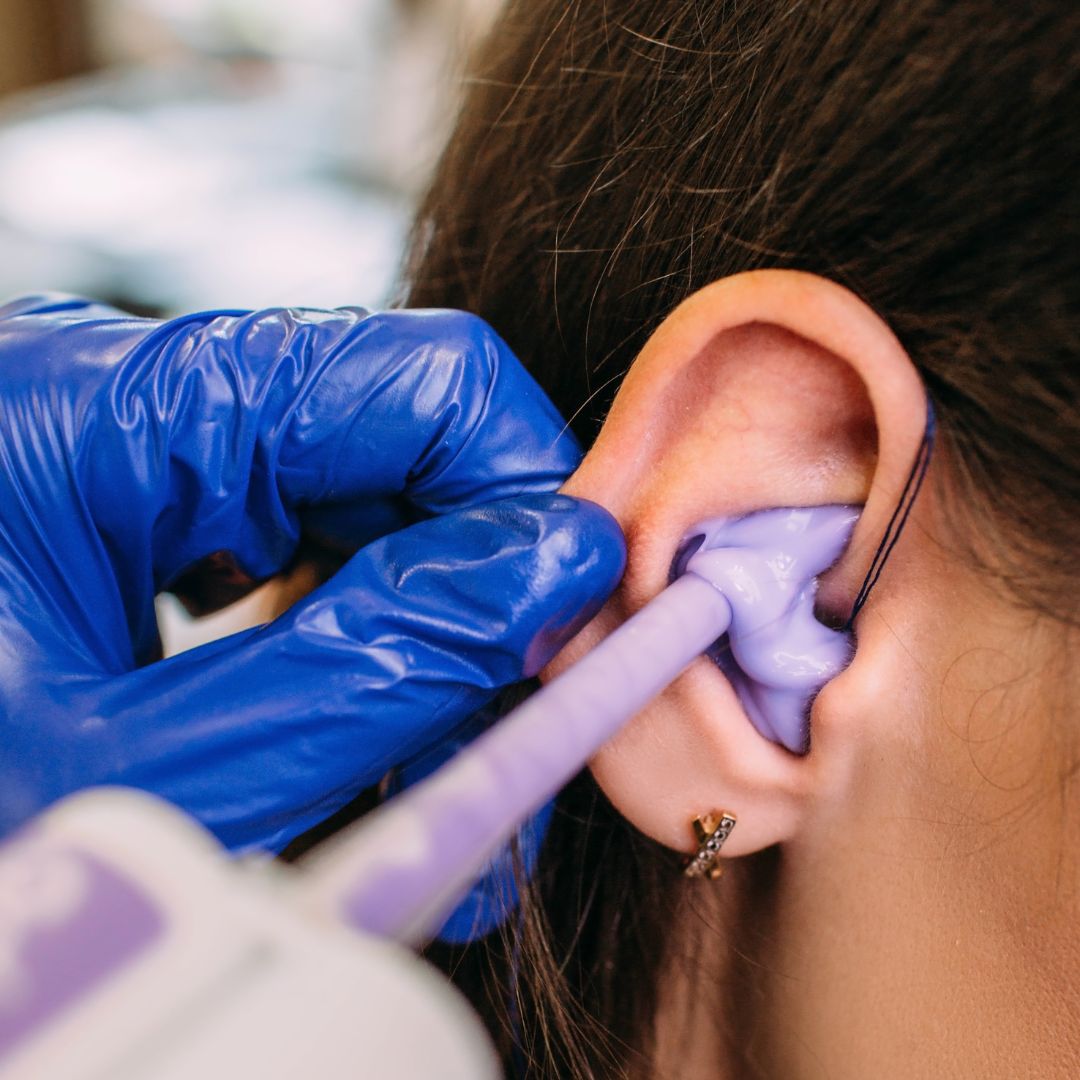 a professional putting molding into a woman's ear to make an impression