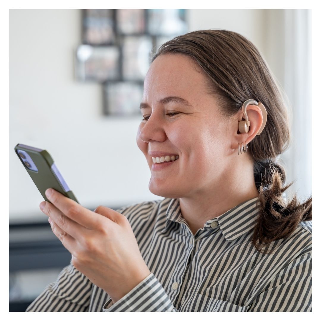 A woman with a hearing aid uses her phone