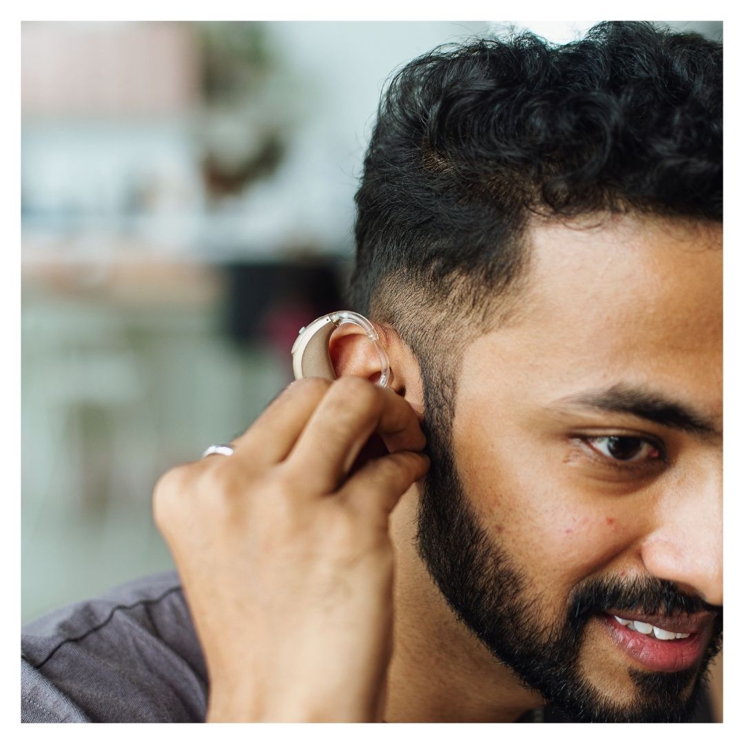 A man adjusts his hearing aid
