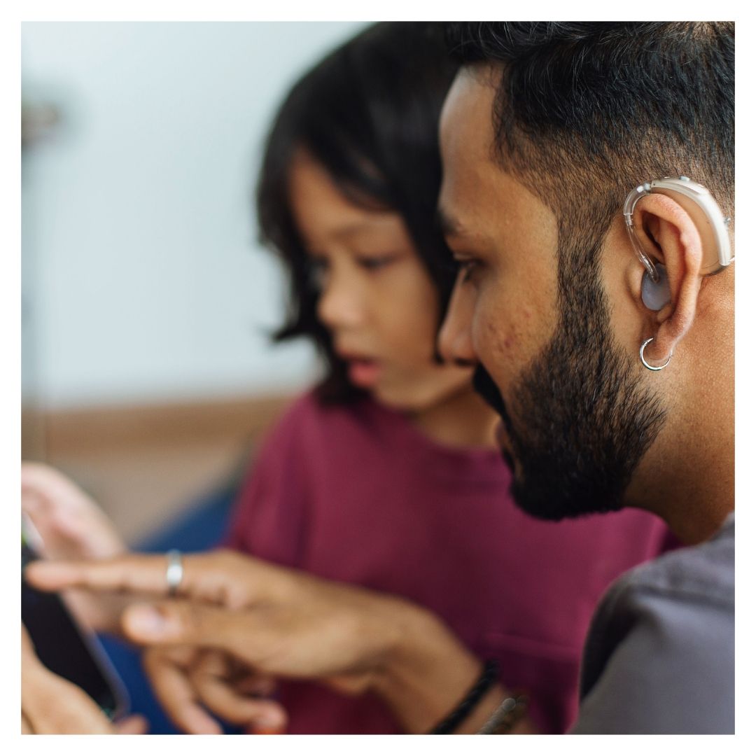 A man with a hearing aid points at his phone
