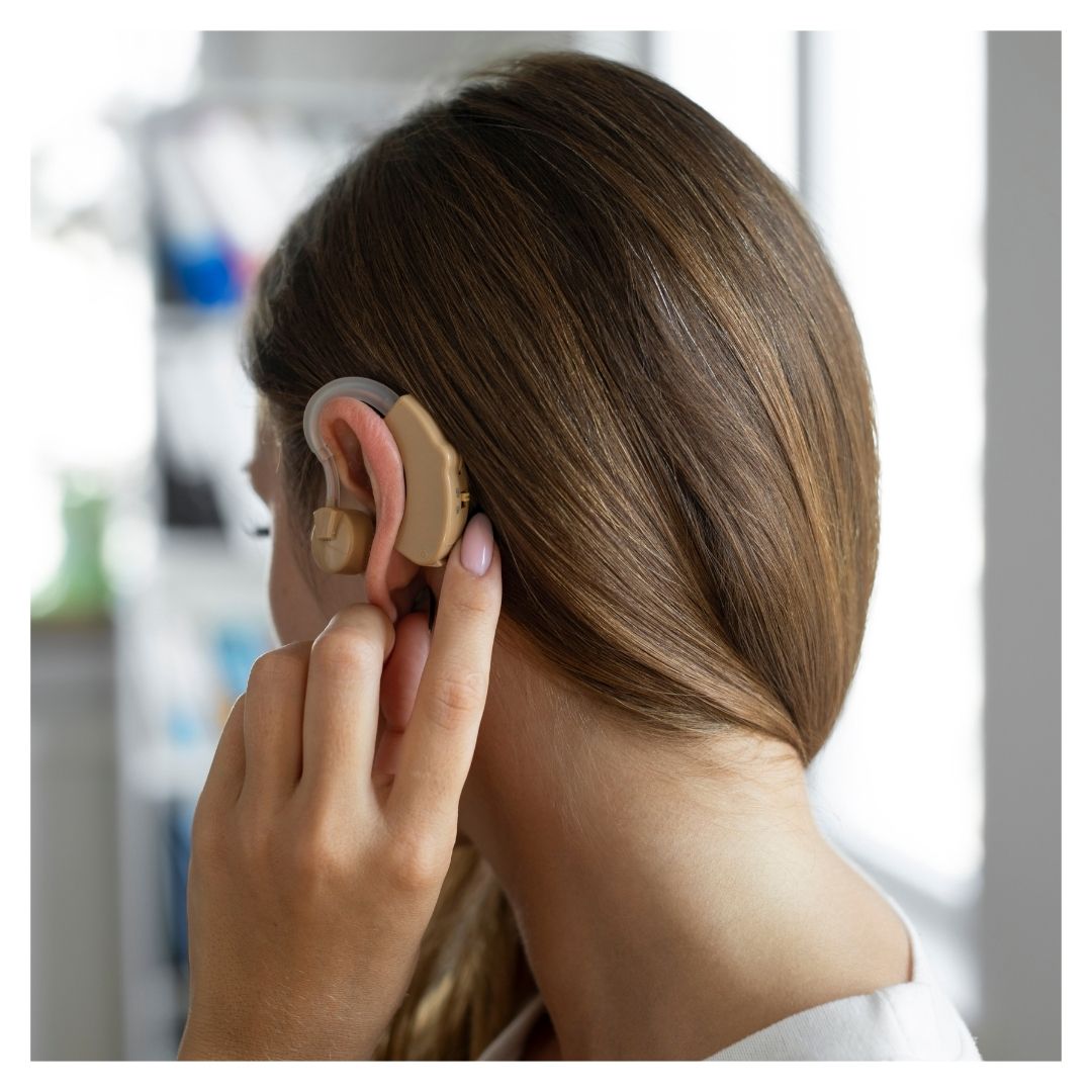 A woman touches her hearing aid