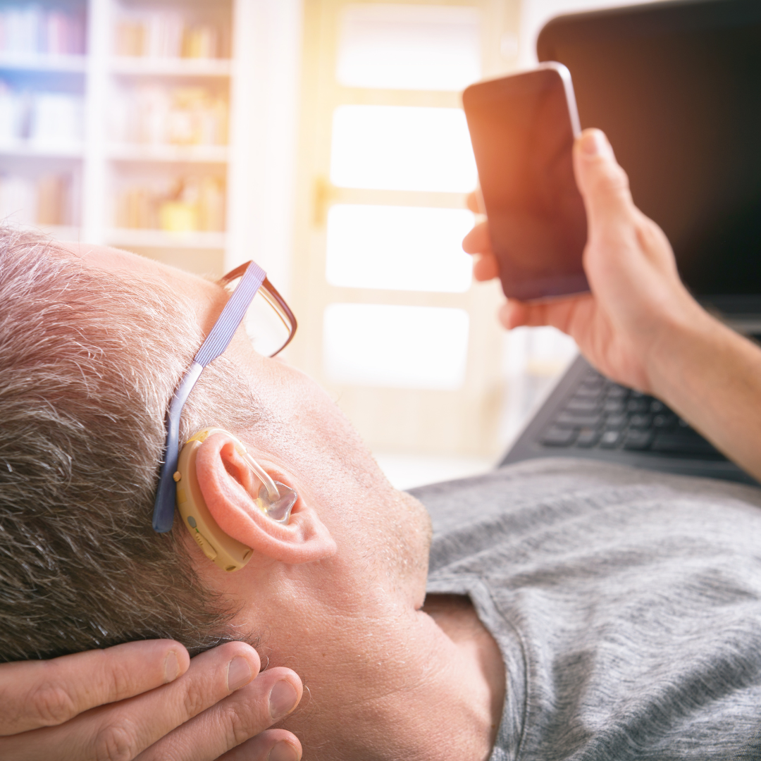 man with hearing add looking at phone