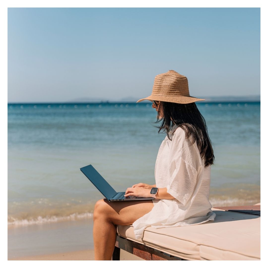 a woman on her laptop at a beach
