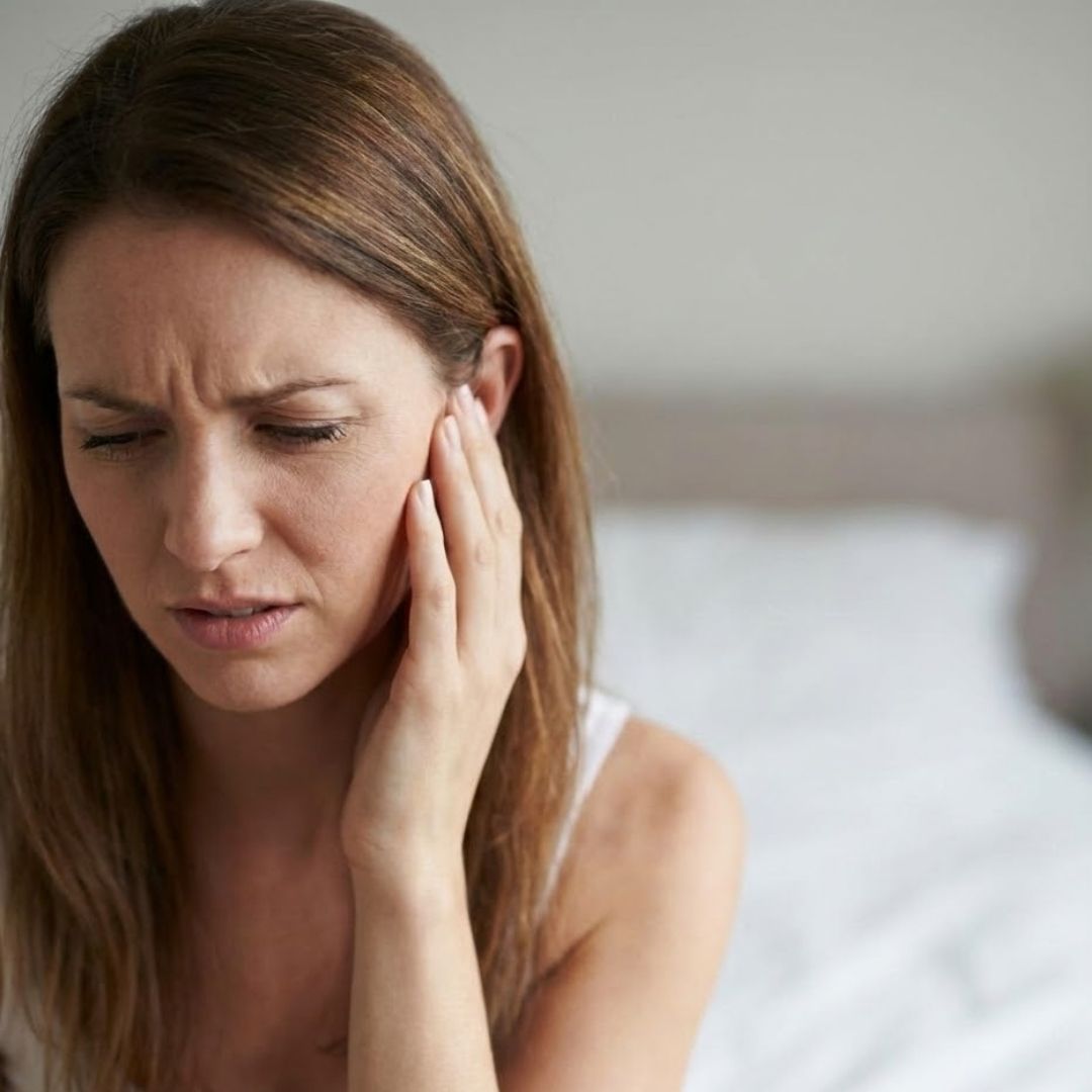Woman in pain holding her hand to her ear.